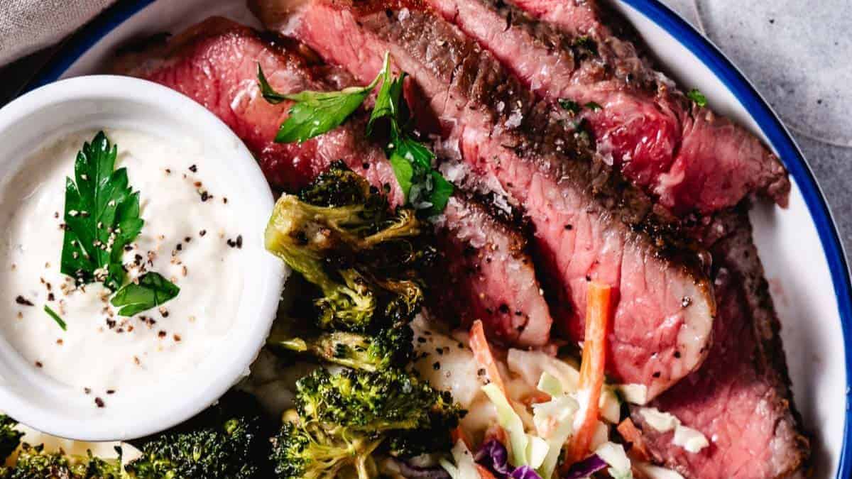 Juicy reverse-seared strip steak with a browned crust and vegetables on a plate.