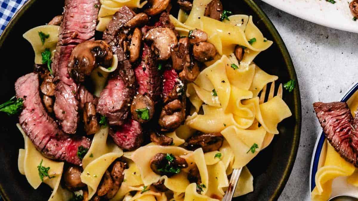 A plate filled with egg noodles and steak. 