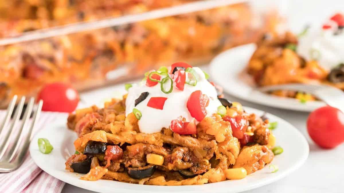 A serving of Taco Bake Casserole set on a plate, with a fork on the side. 