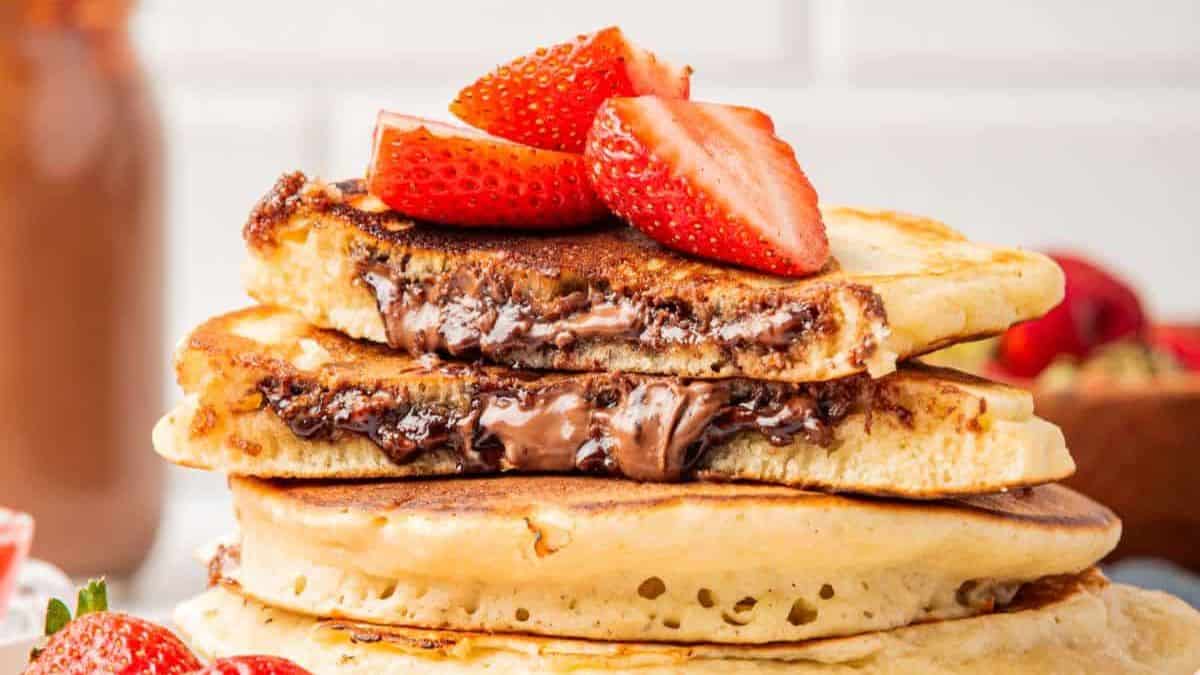 Stack of Nutella filled pancakes with slices of fresh strawberries on top. 