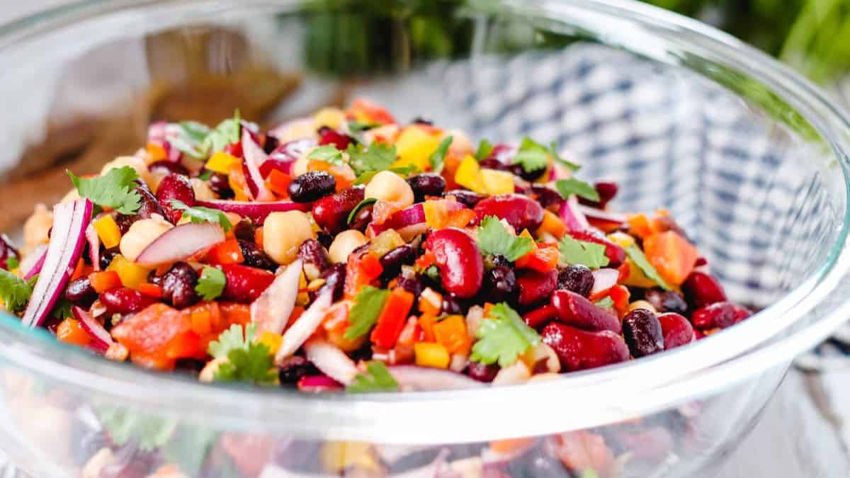 A close-up shot of a clear bowl filled with three-bean salad. 