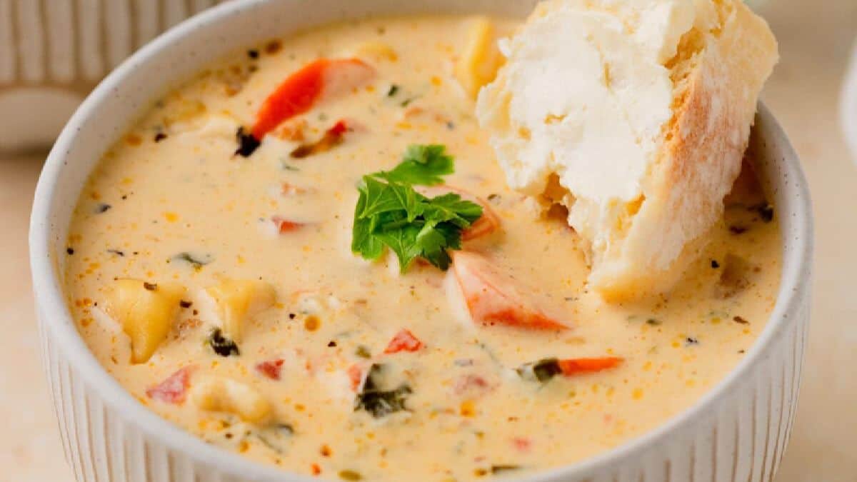 A close-up shot of a bowl filled with cream soup and a slice of crusty bread on the side.