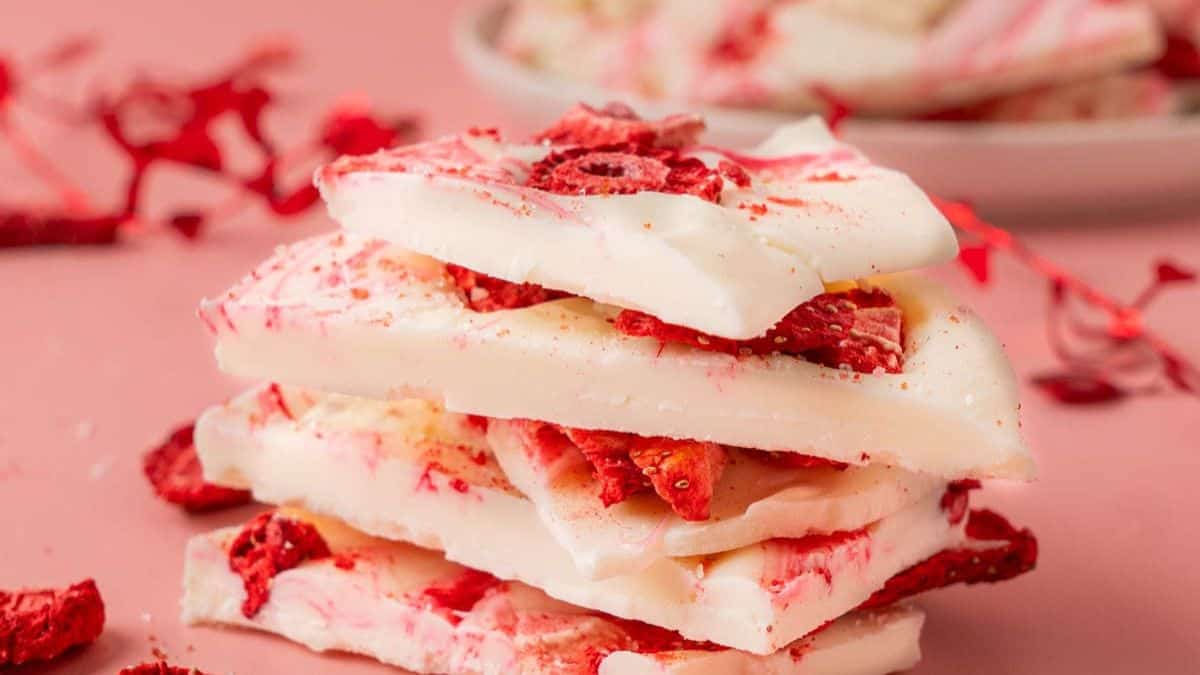 A close-up shot of four pieces of white chocolate strawberry bark that are stack on top of each other. 