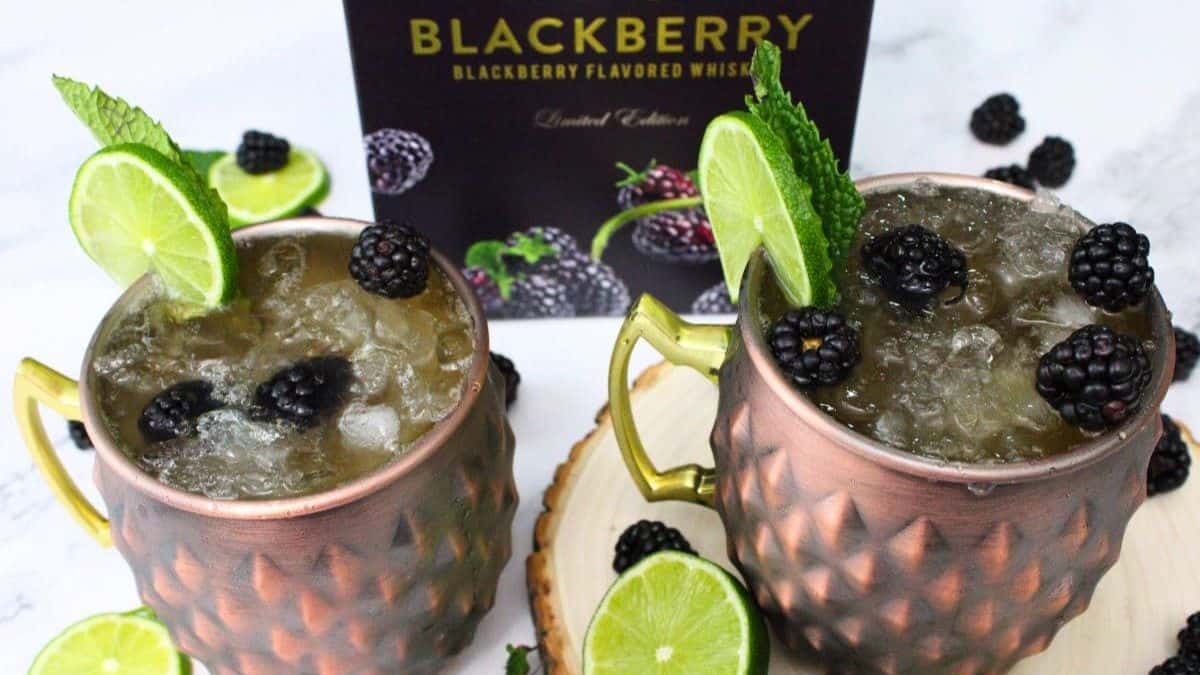 Two servings of Blackberry Kentucky Mule topped with a slice of lime and a few pieces of blackberries. 