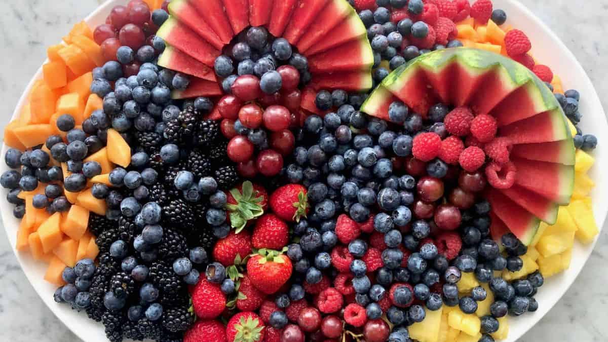 Fruit platter filled various fruits: watermelon, blueberries, cantaloupes, blackberries, raspberries, strawberries, pineapple, grapes. 