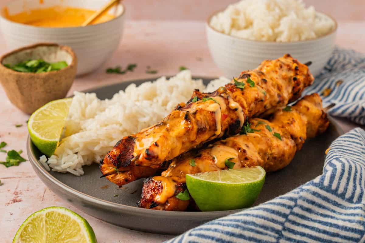 The chicken skewers with rice and lime wedges. 