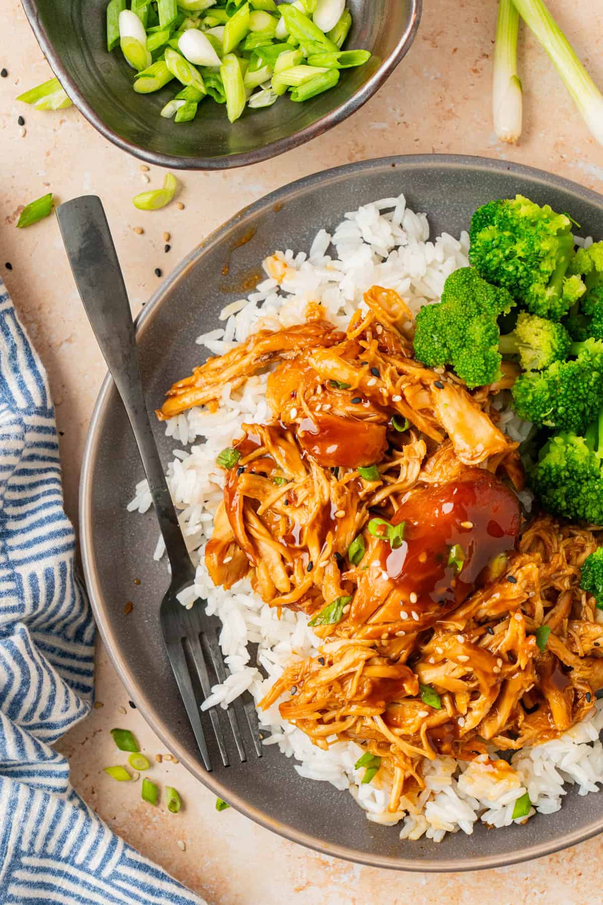 A plate with honey garlic chicken over rice with broccoli. 
