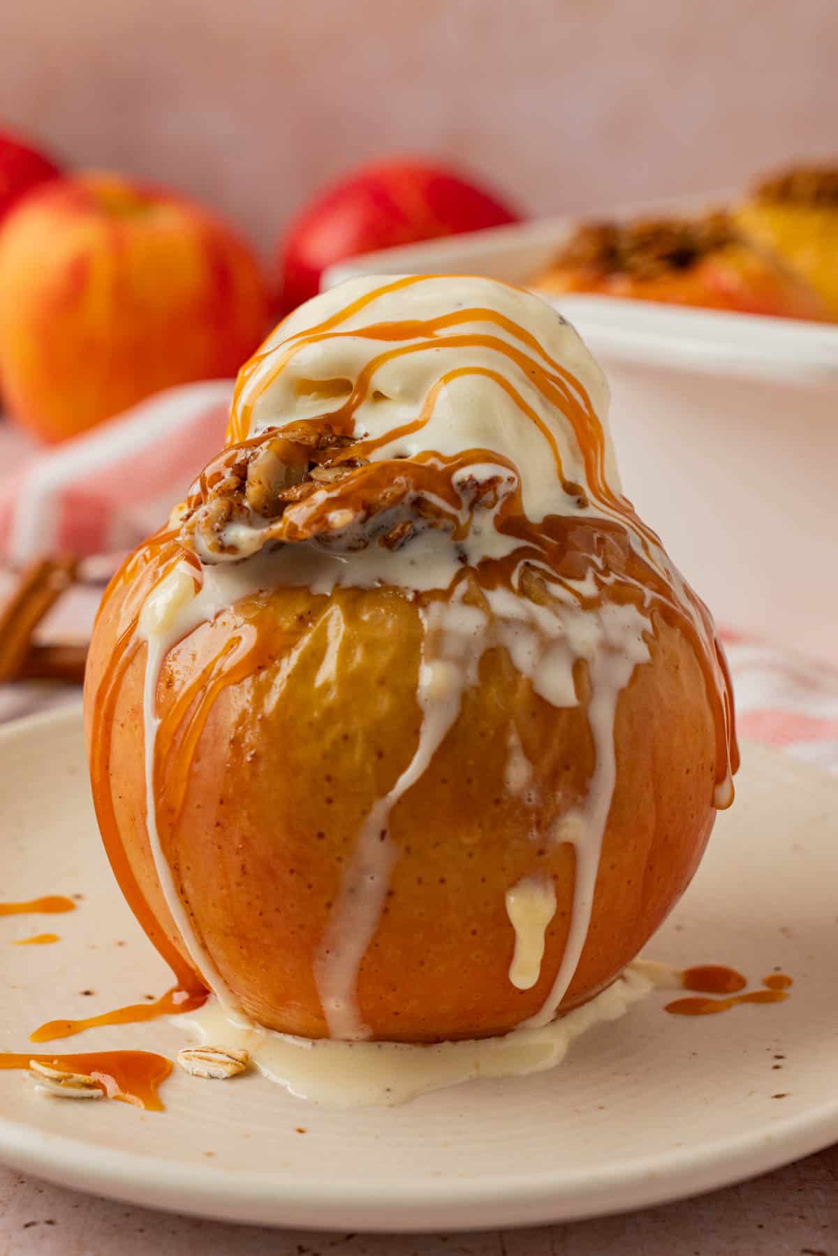 Baked apple topped with melting vanilla ice cream and caramel sauce on a plate