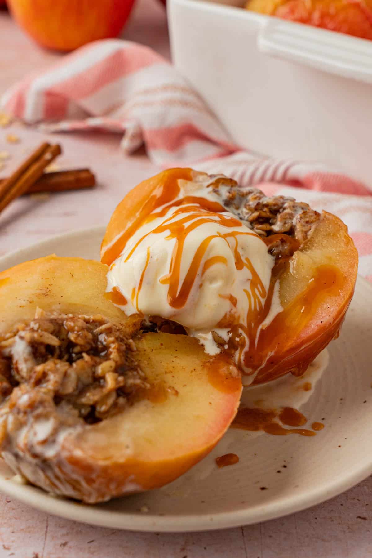Close-up of a halved baked apple with oat filling, topped with melting ice cream and caramel drizzle