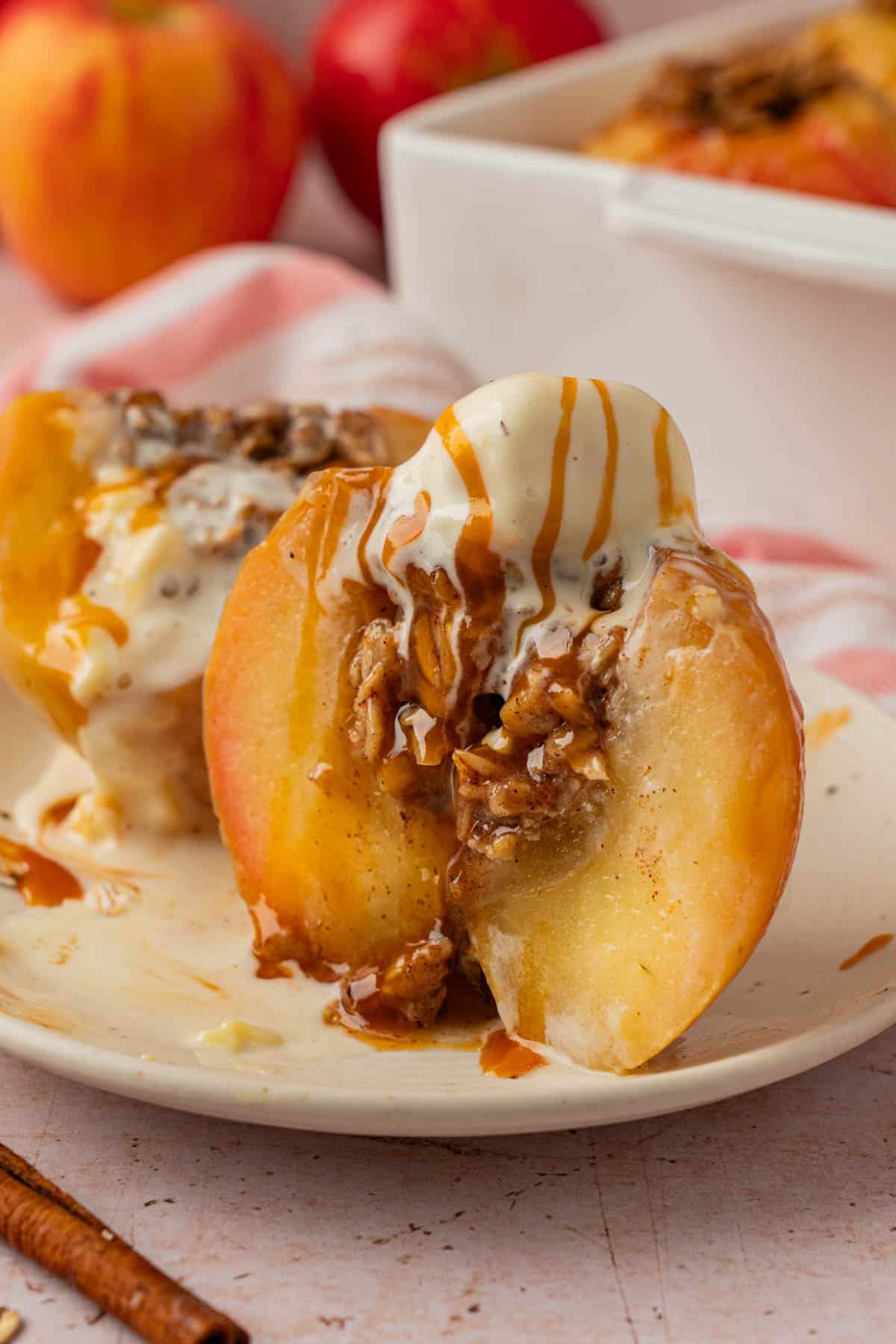 Baked apple sliced in half showing tender oat filling, topped with vanilla ice cream and caramel