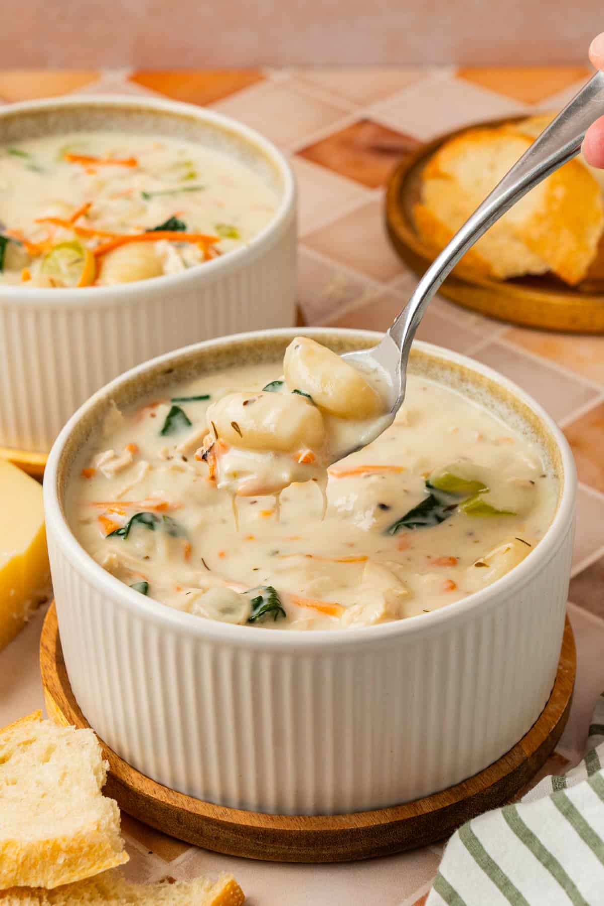 The soup in a bowl with a spoonful of chicken gnocchi soup. 