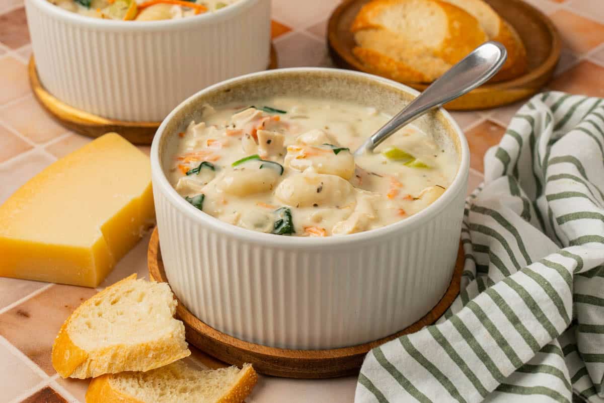 A bowl of chicken gnocchi soup with carrots, celery and spinach in a creamy sauce. 