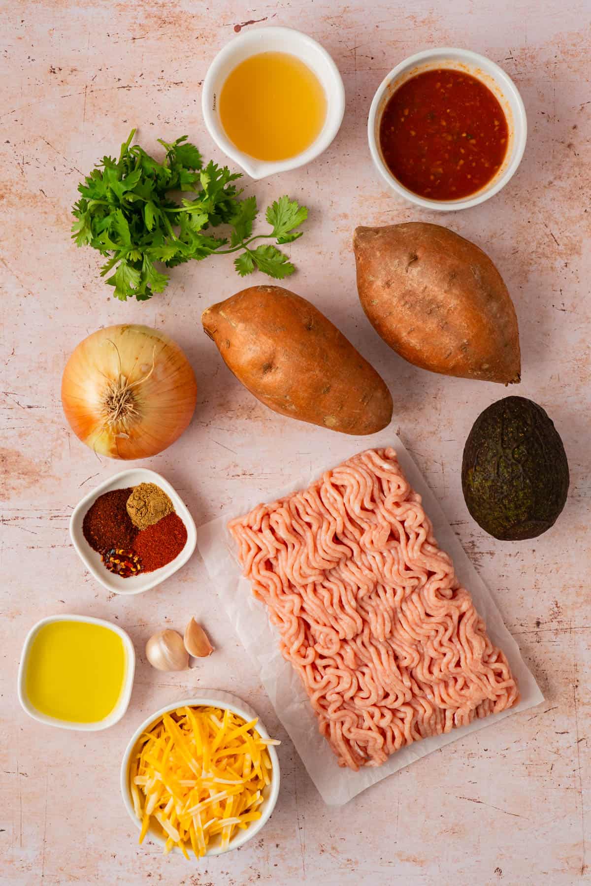 Ingredients for a turkey sweet potato skillet: ground turkey, sweet potatoes, onion, garlic, spices, salsa, broth, and cheese.