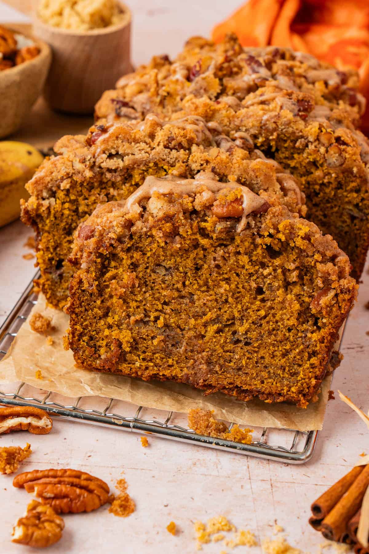 Sliced pumpkin banana bread with pecan streusel topping and cinnamon glaze drizzle, showing the moist interior crumb up close