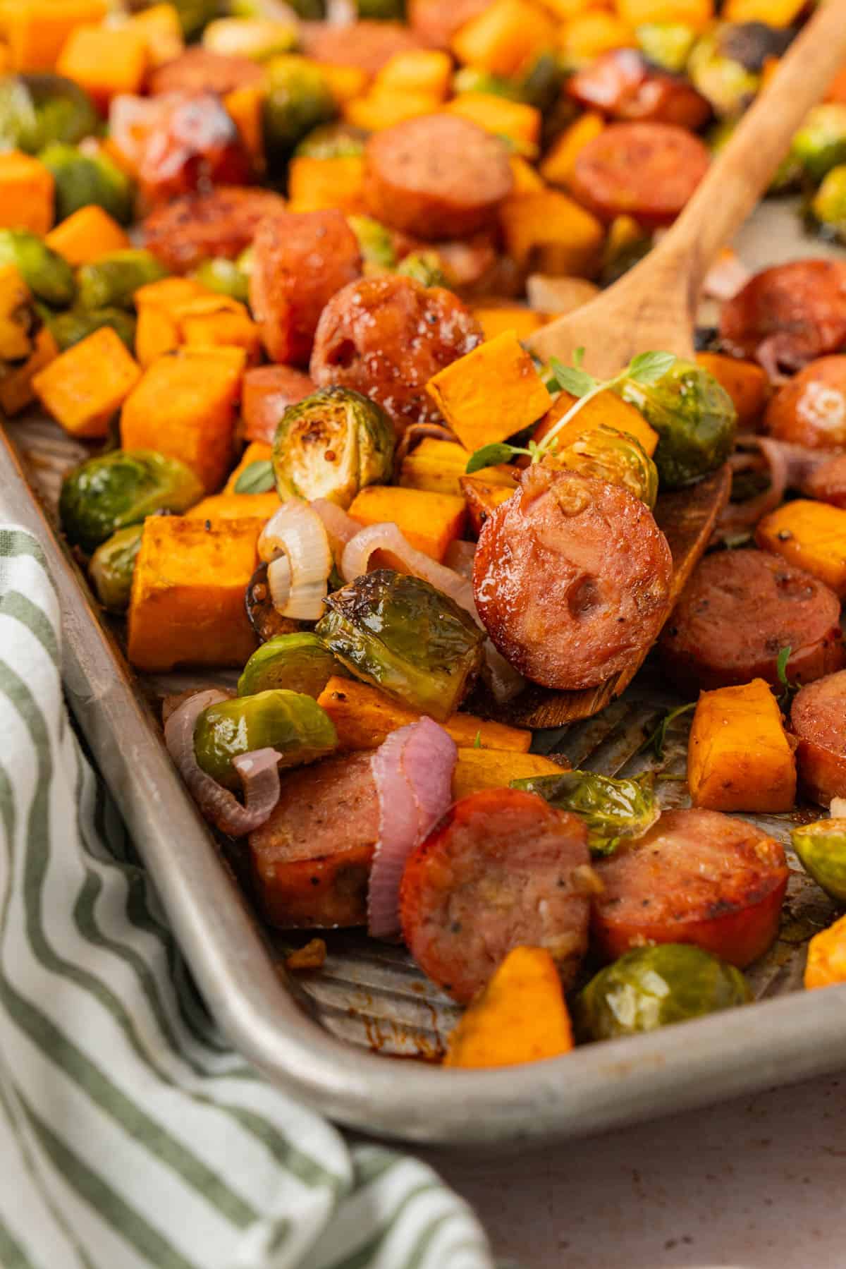 Close-up of a chicken sausage sweet potato sheet pan dinner with caramelized sausage, Brussels sprouts, and fresh thyme.