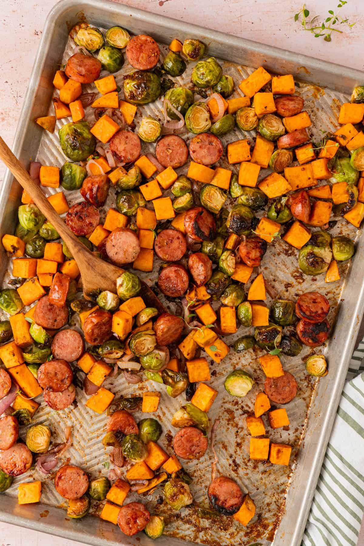 Overhead view of sheet pan chicken sausage and veggies with roasted sweet potatoes, Brussels sprouts, and shallots.