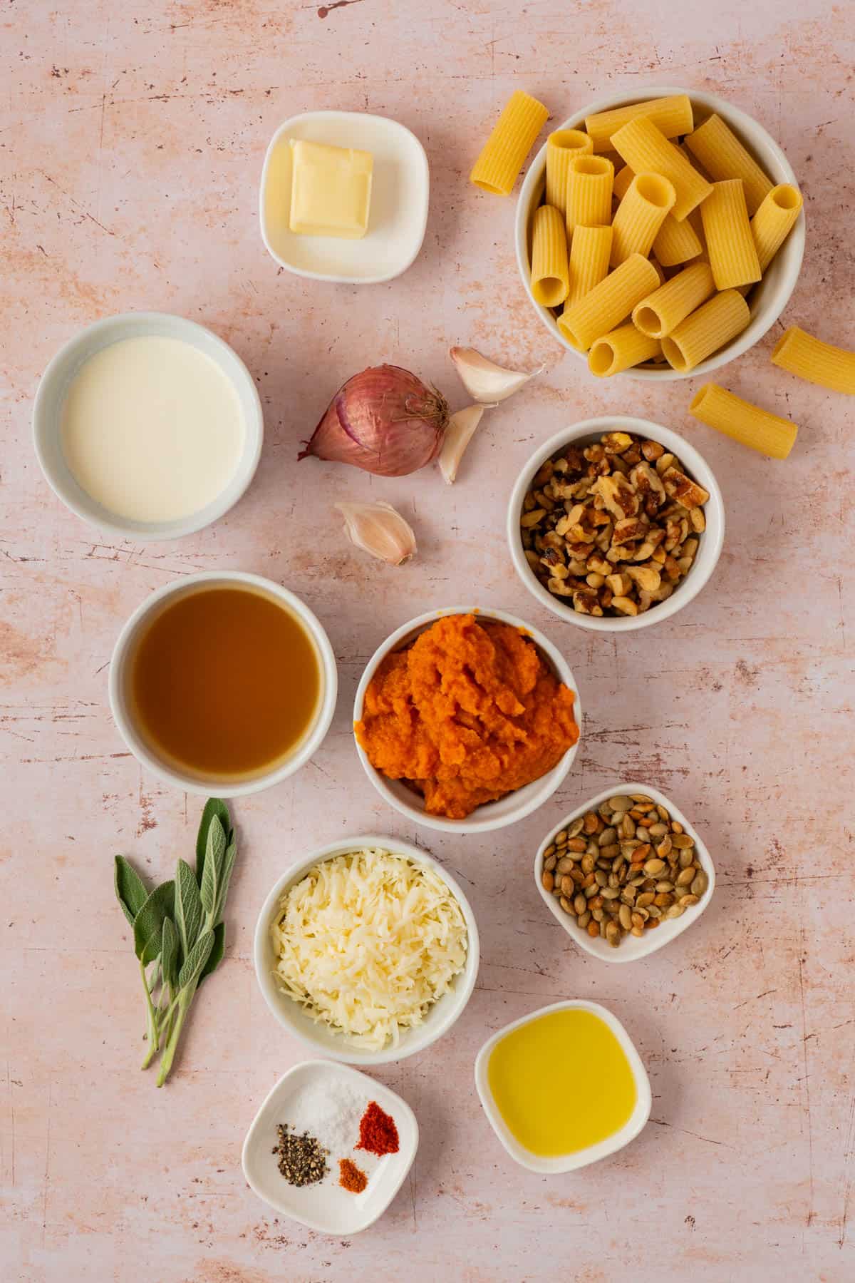 Ingredients for pumpkin pasta recipe: rigatoni, pumpkin puree, heavy cream, Gruyere, sage, walnuts, pepitas, and spices.