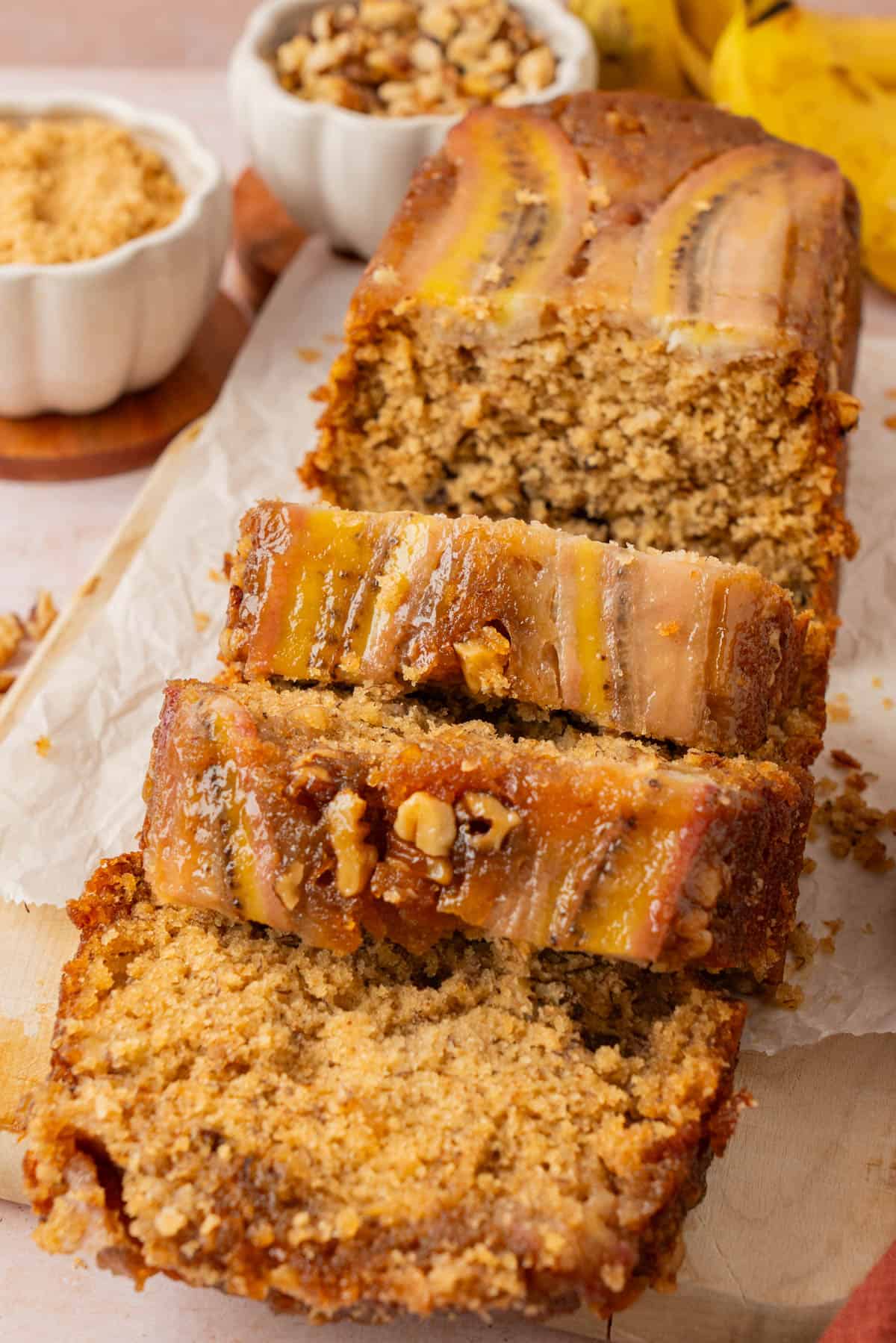 Caramel banana bread sliced to show the moist crumb and glossy caramel banana topping