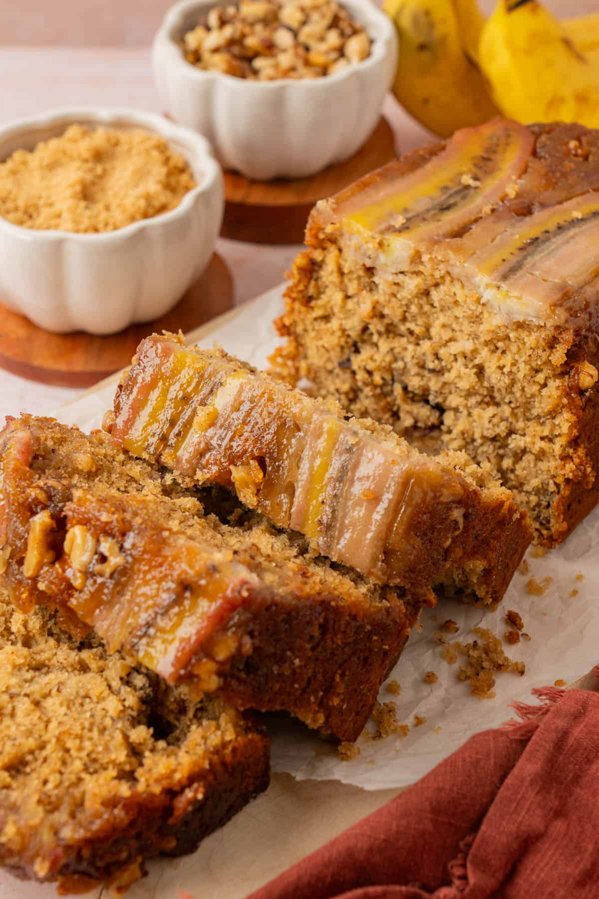 Close up of banana bread caramel topping with sticky walnuts on thick slices of brown butter banana bread