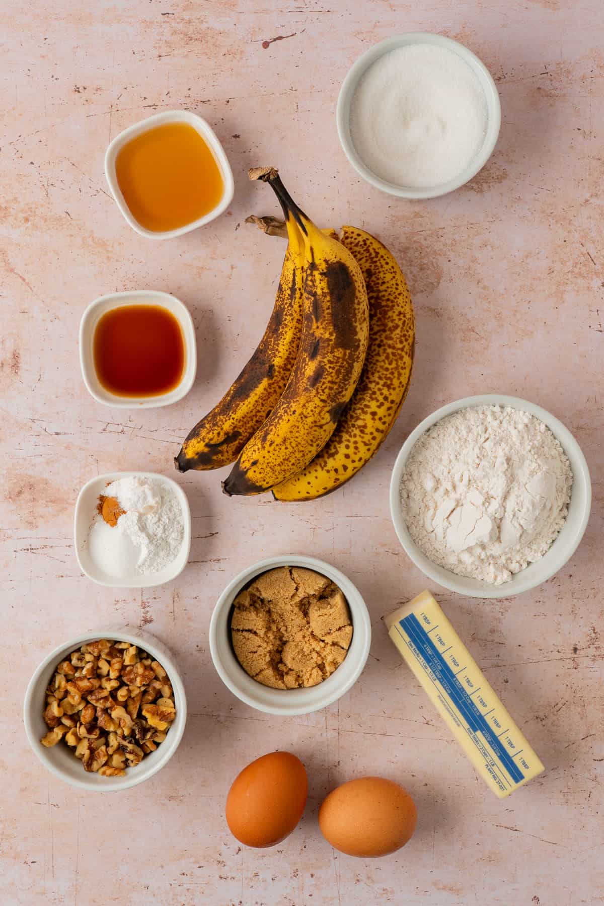 Ingredients for caramel banana bread including ripe bananas, butter, brown sugar, walnuts, maple syrup and flour