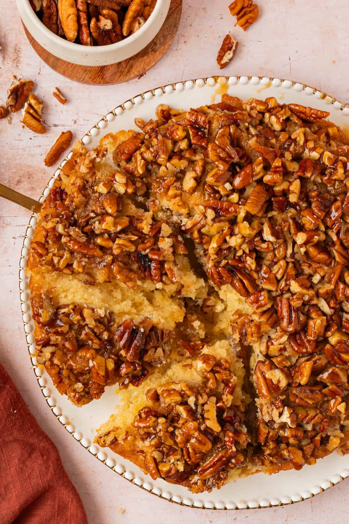 Overhead view of a sliced caramel upside down pecan cake showing the soft, tender vanilla cake under the pecan topping.