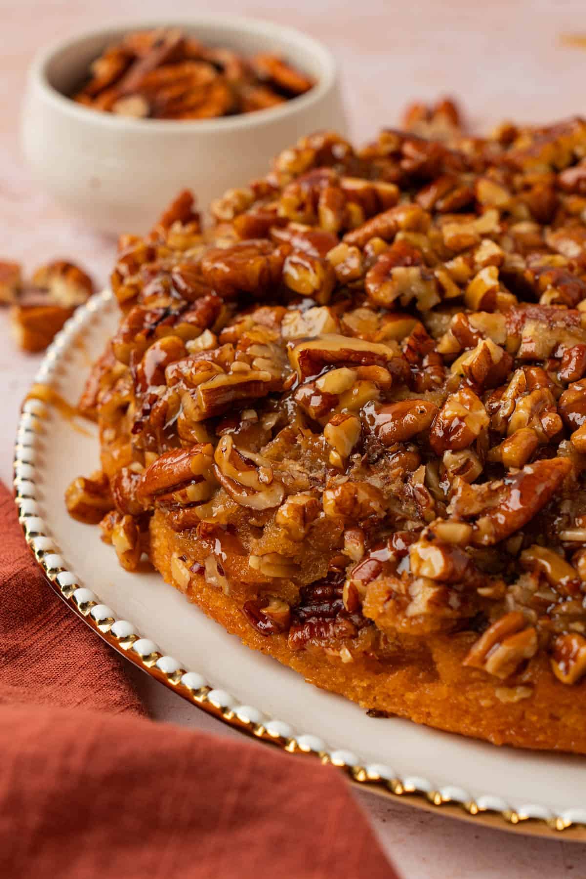 Close-up of a caramel pecan upside down cake showing glossy caramel-coated chopped pecans over a golden cake layer.